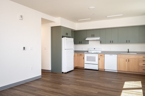 an empty kitchen with white appliances and wood floors