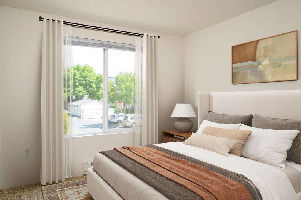 A bedroom with a large bed and a painting on the wall.