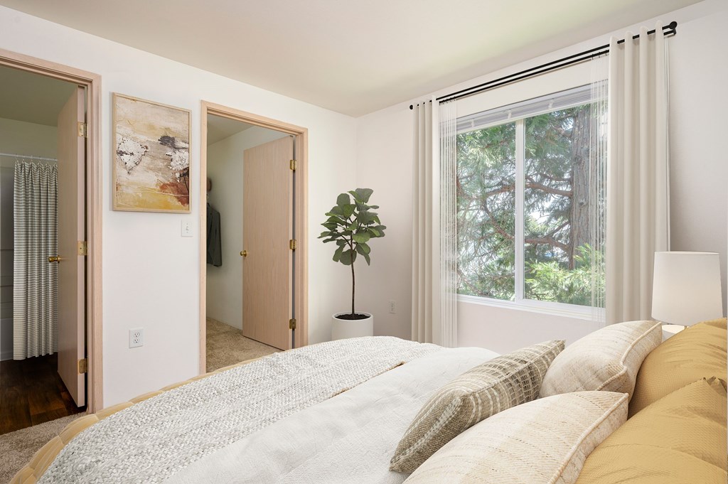 A bedroom with a large bed and a window with a view of trees.