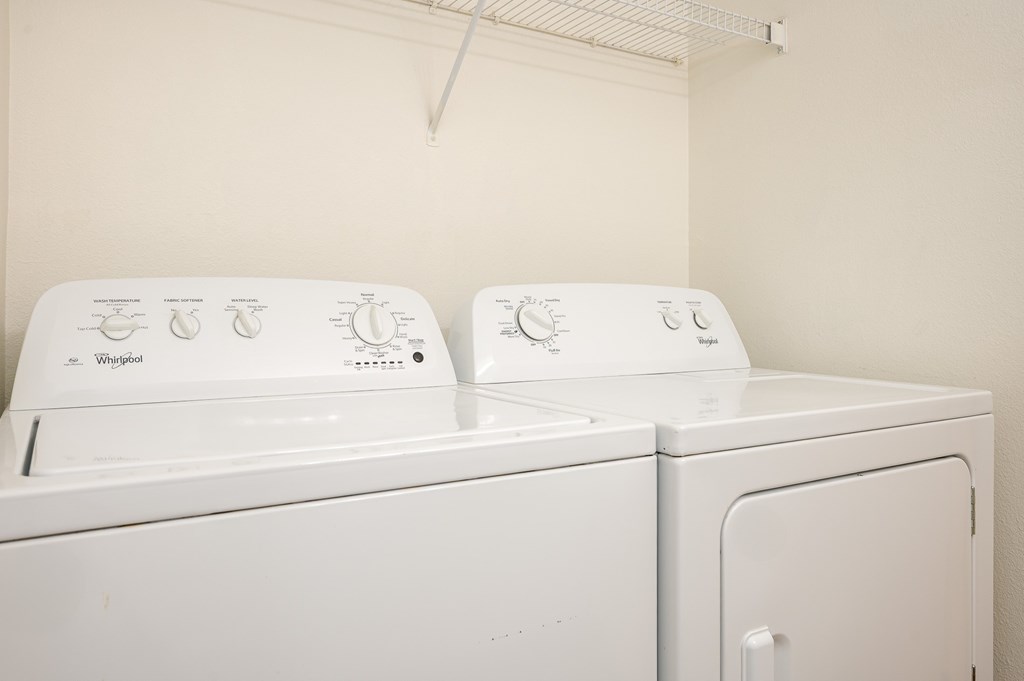 Two white Whirlpool washing machines in a laundry room.