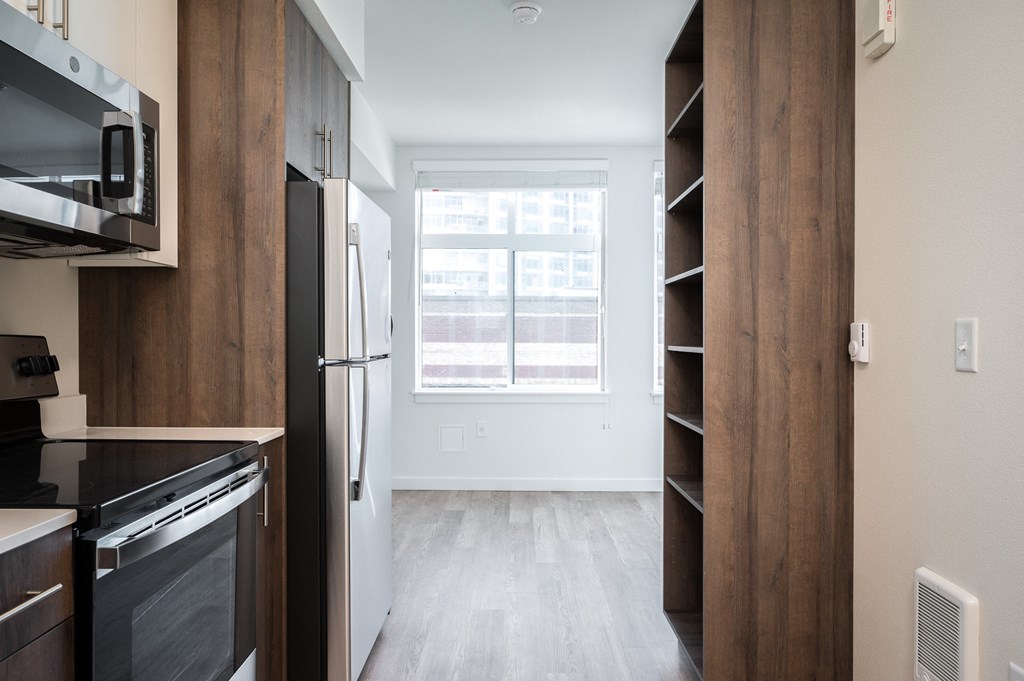 a kitchen with a large window and a refrigerator and a book shelf