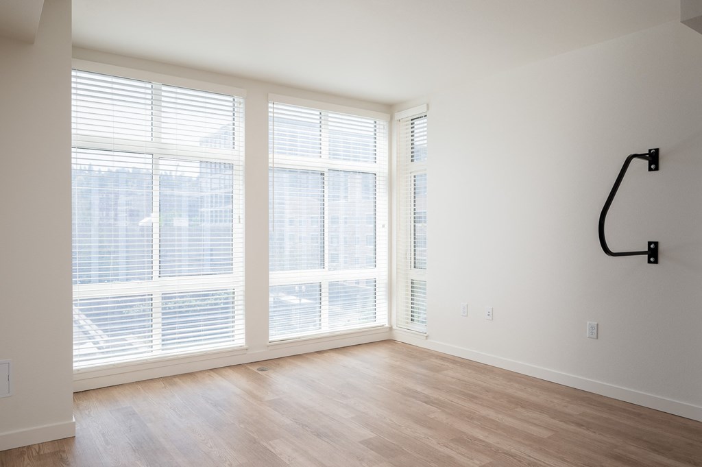 an empty living room with large windows and a wood floor