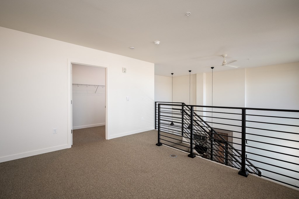 a room with white walls and a railing and a closet