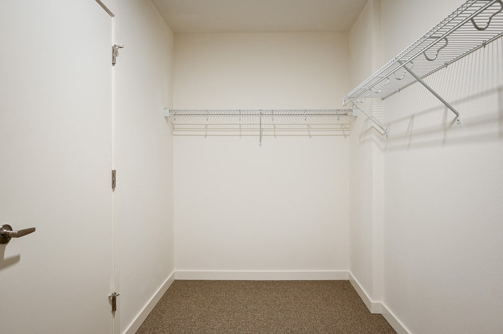 a room with white walls and a closet with wire shelving