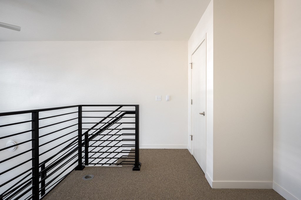 a stairwell in a home with a black railing and white walls