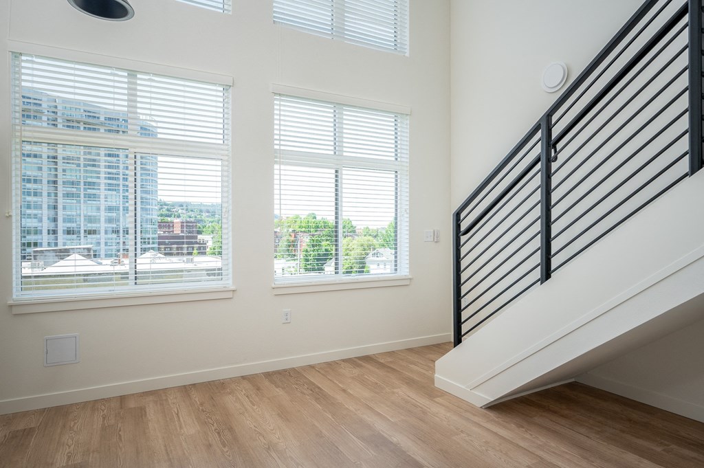 a living room with three windows and a staircase