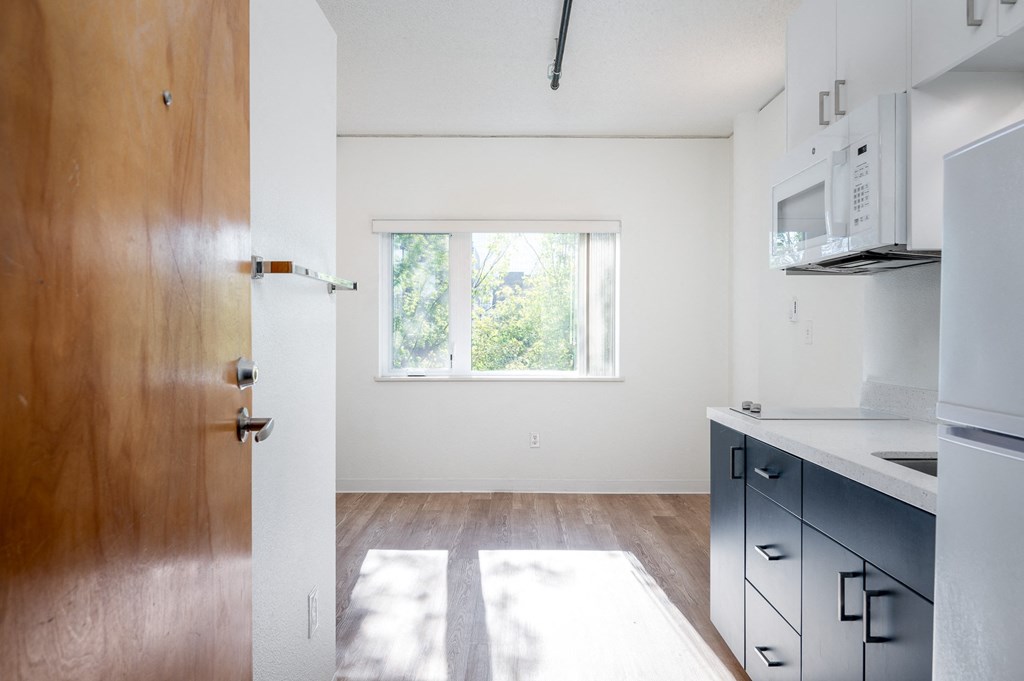 a kitchen with white walls and a wooden floor