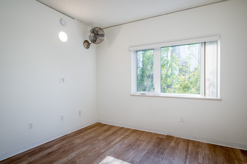 a bedroom with hardwood floors and a large window