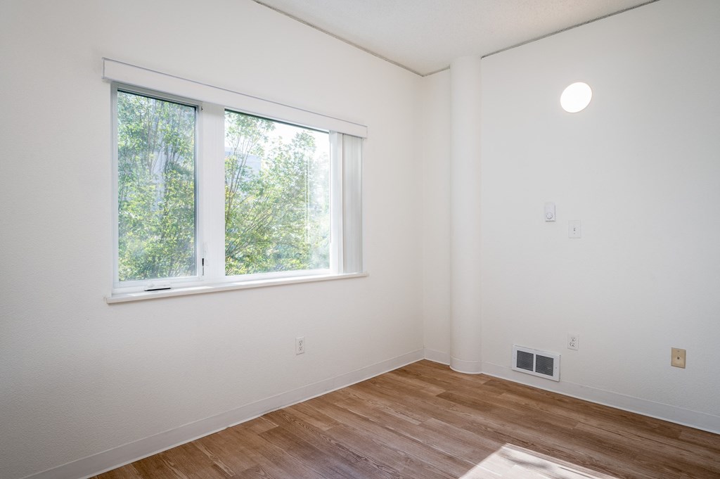 a bedroom with a large window and hardwood floors