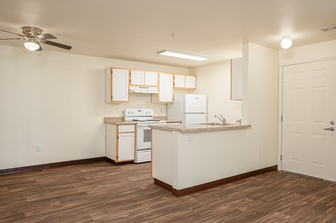 A kitchen with white cabinets and a wooden floor.