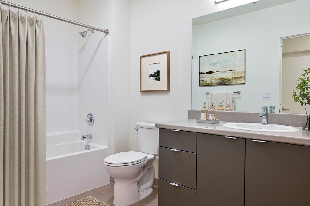 a bathroom with a white bathtub and a white toilet next to a sink with a mirror