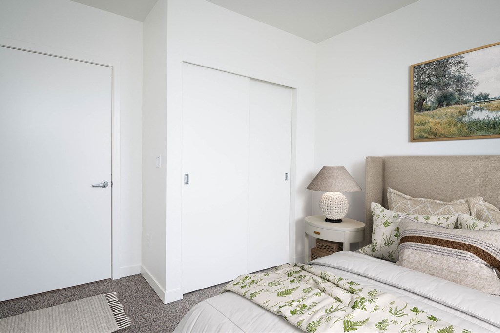 a bedroom with white walls and a bed with green and white bedding