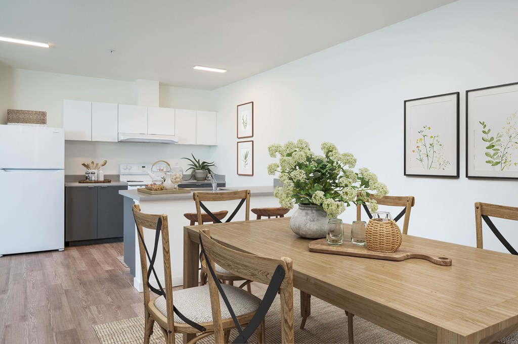 a dining area with a wooden table and chairs and a kitchen in the background