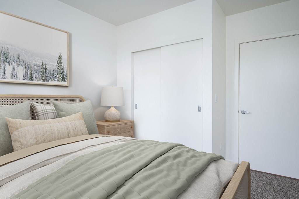 a bedroom with white walls and a bed with gray and white bedding