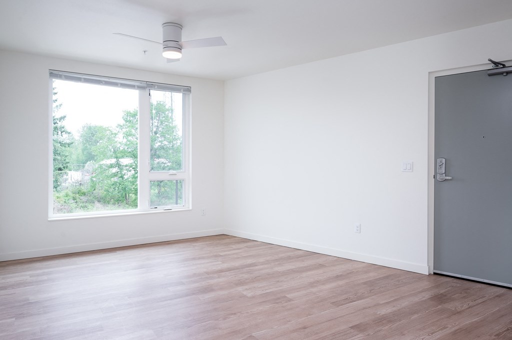 an empty room with a large window and wooden floors