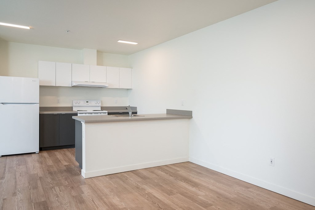 a kitchen with white walls and a wooden floor