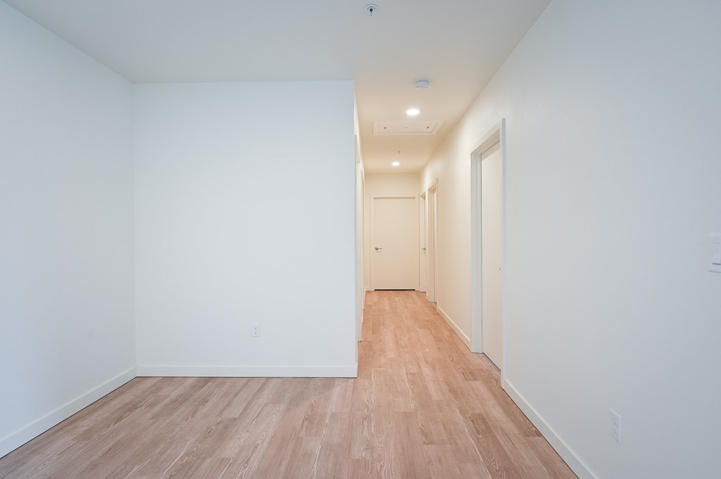 a bedroom with hardwood floors and white walls