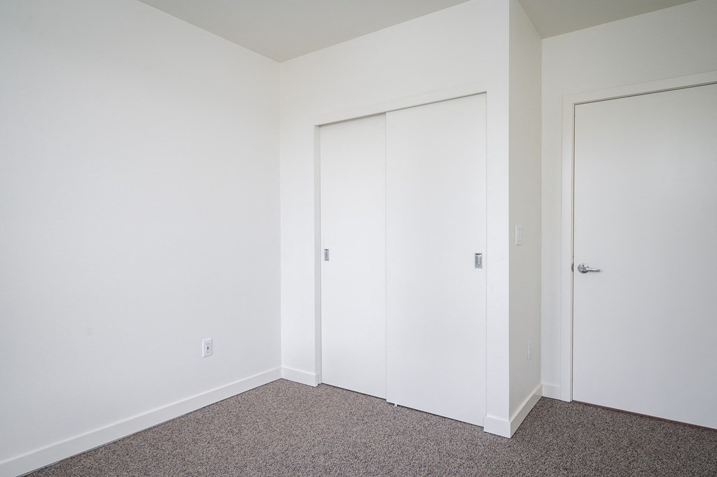 a bedroom with white walls and carpet