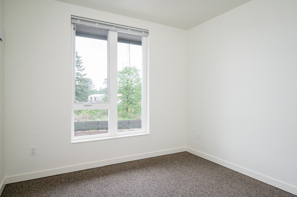 a bedroom with a large window and a carpeted floor