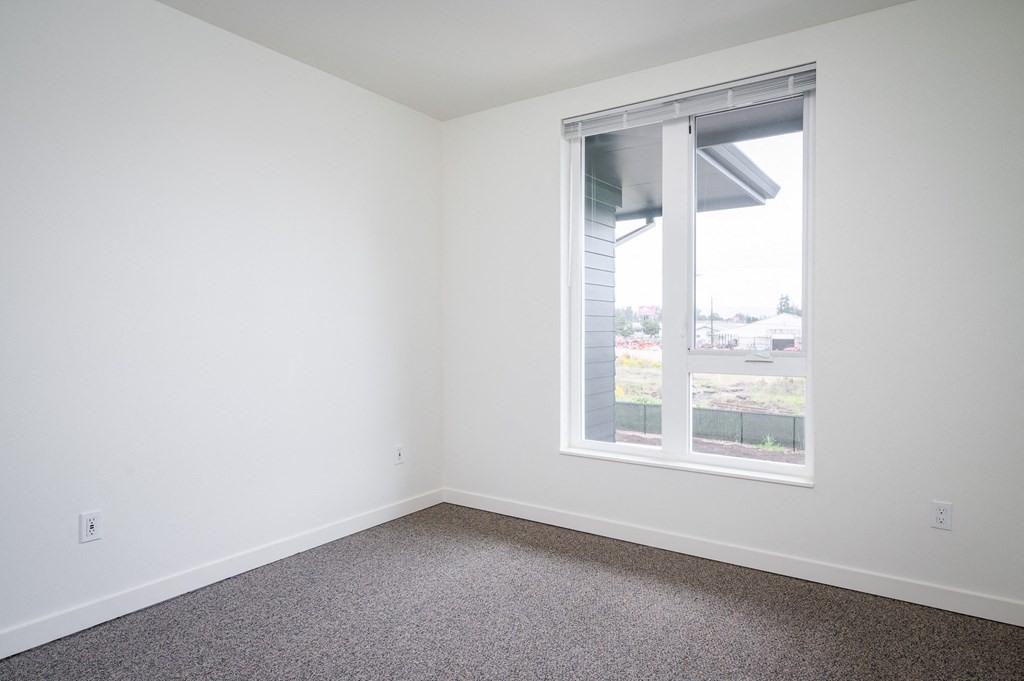 a bedroom with a large window and carpet