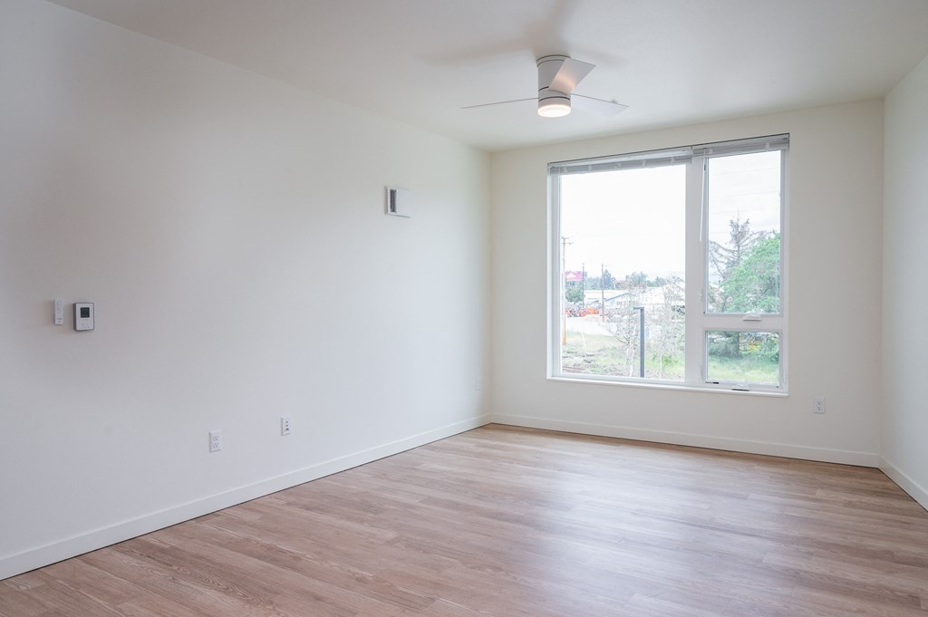 a bedroom with a large window and hardwood floors