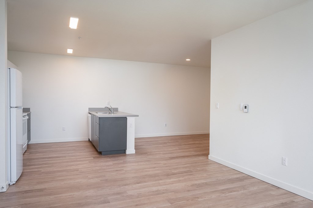 a kitchen and living room with white walls and wood floors