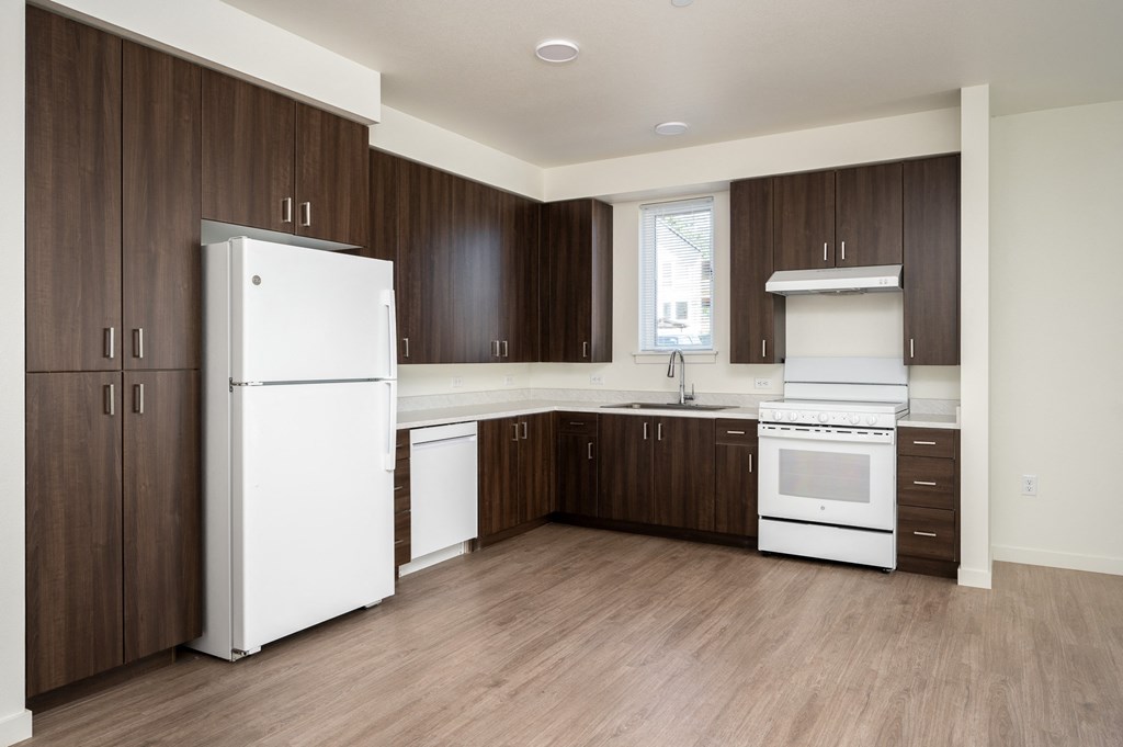 an empty kitchen with white appliances and wooden cabinets