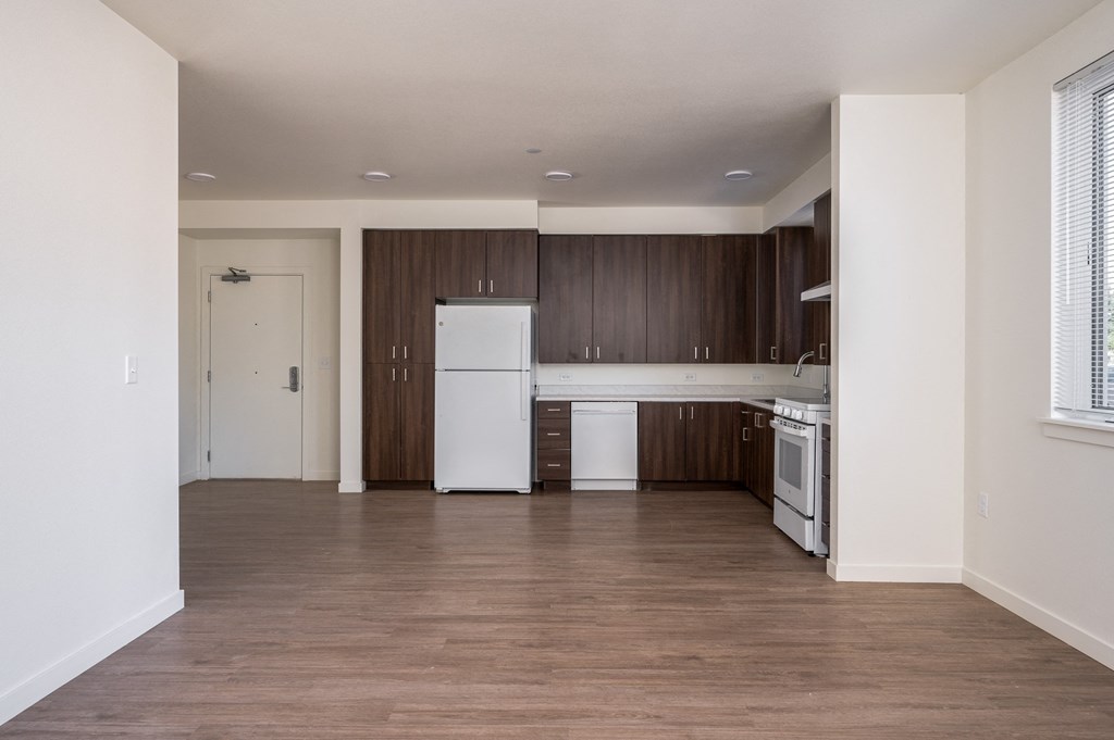 an empty kitchen with white appliances and wood flooring in an apartment