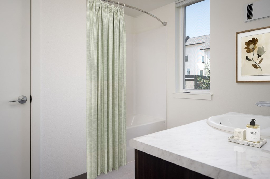 a bathroom with a shower and a sink and a window
