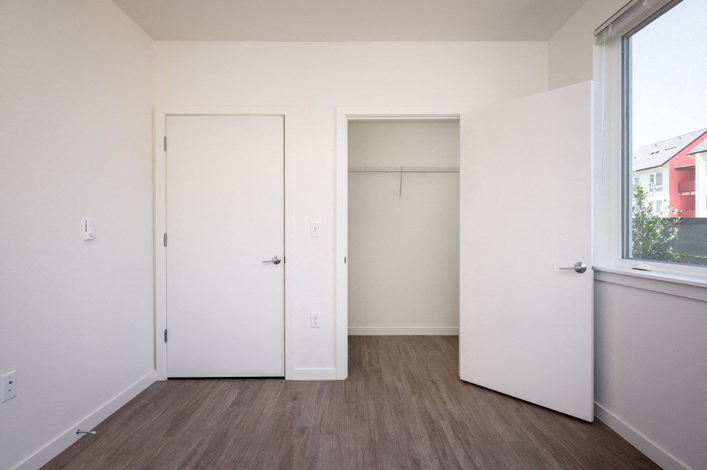 a bedroom with white walls and a window and a closet