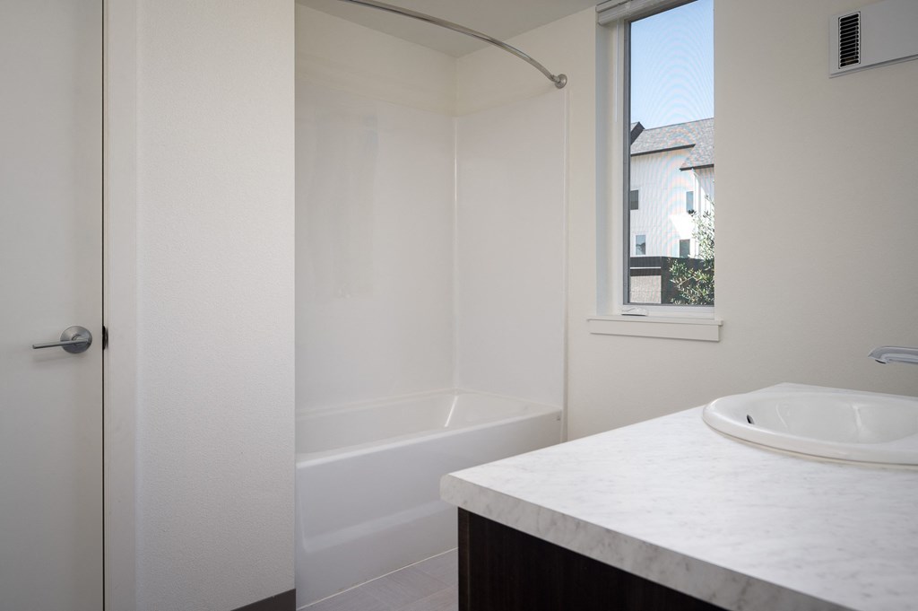 a bathroom with a sink and a shower and a window