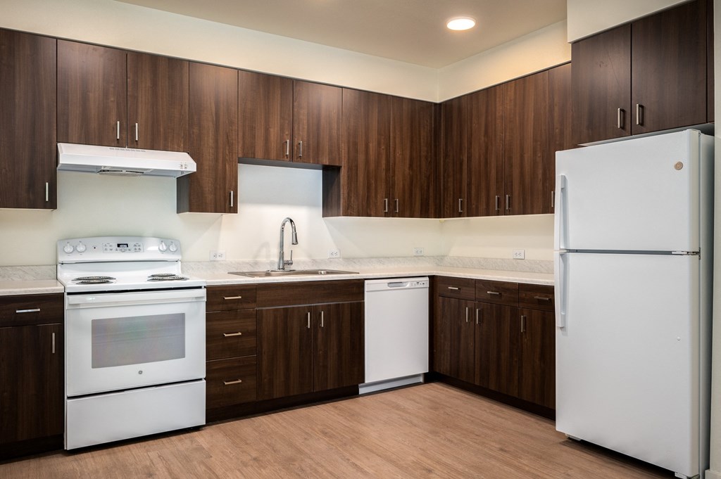 an empty kitchen with white appliances and wooden cabinets
