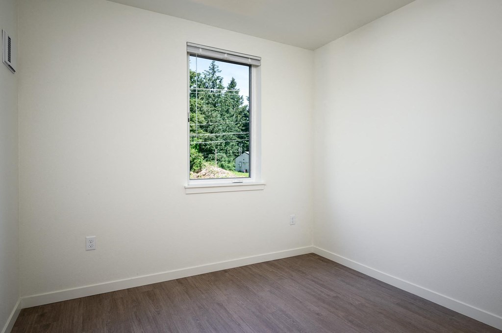 a white room with a window and wooden floors