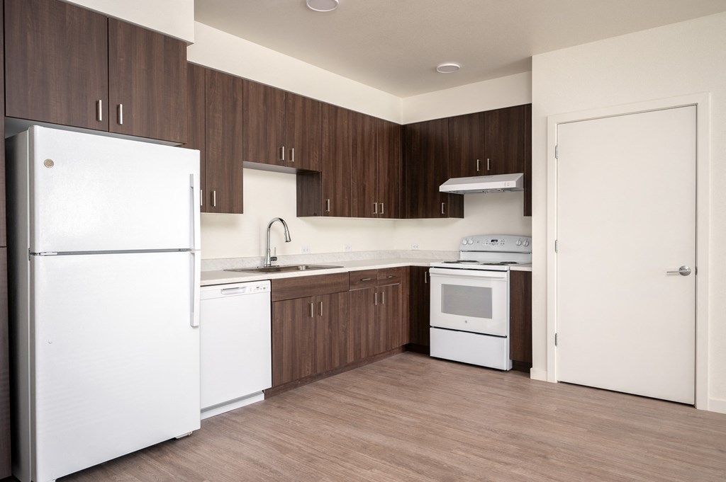 an empty kitchen with white appliances and wooden cabinets