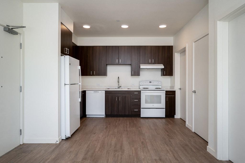 an empty kitchen with white appliances and dark wood cabinets