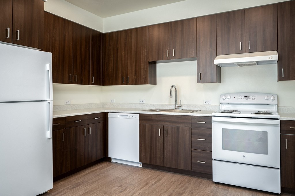 an empty kitchen with white appliances and wooden cabinets