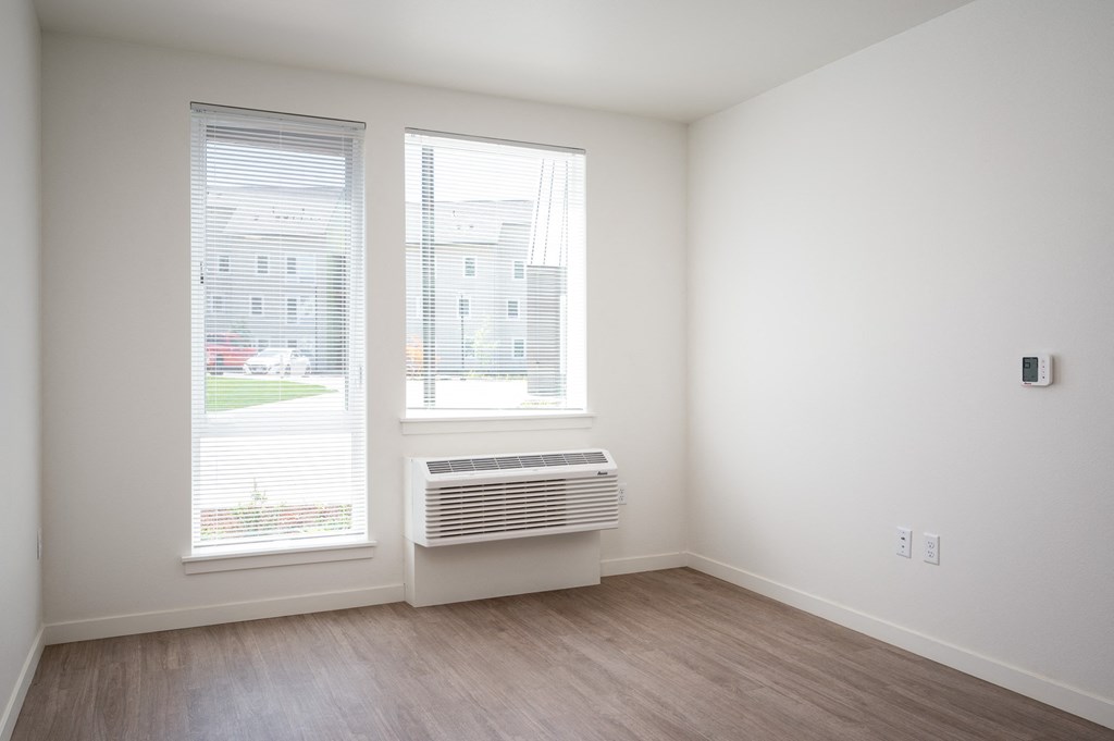 an empty room with two windows and a heater in the corner