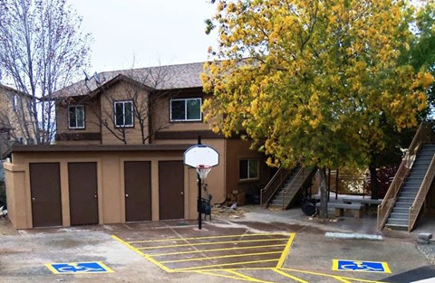 A basketball court with a hoop and two handicap parking spaces.