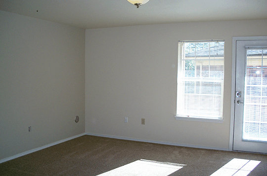 an empty living room with a door and window