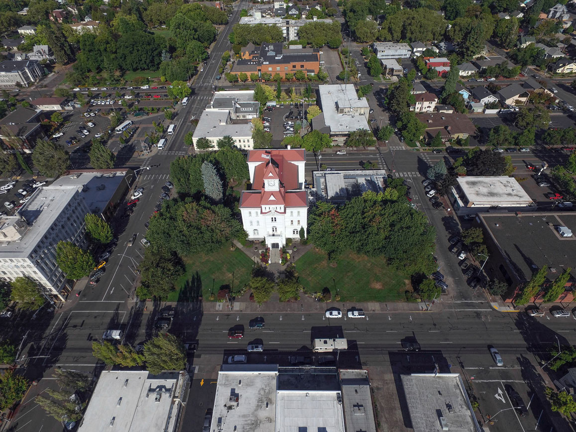 a large white building with a red roof sits in the middle of a city street