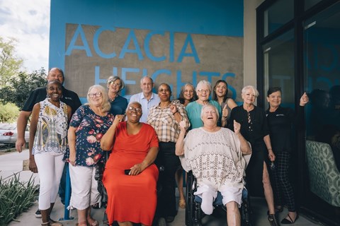 A group of people are standing in front of a blue wall with the words "ACACIA HEALTH" written on it.