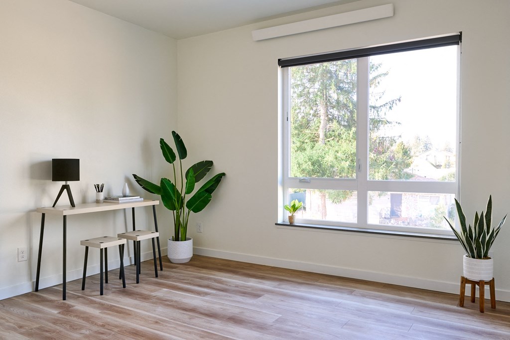 a living room with a large window and a desk with three stools