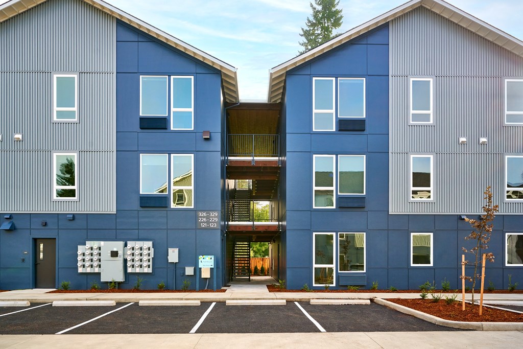 a row of blue apartment buildings with a parking lot