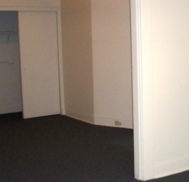 A white door is open to a room with a carpeted floor.