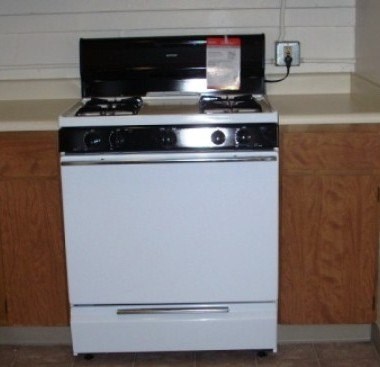 A white oven with a black stove top sits on a kitchen counter.