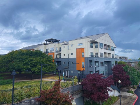 A modern building with a mix of grey and orange accents sits in a residential area.