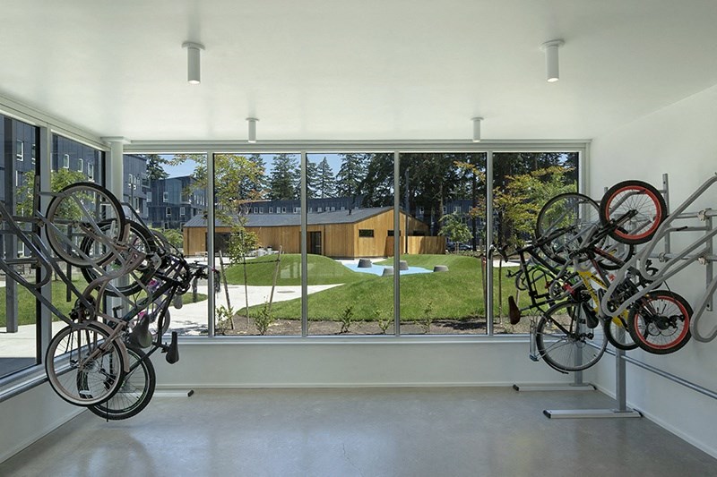a room with bikes hanging on the wall and a large window with a view of a yard