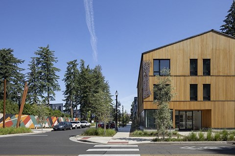 a city street with a yellow building on the left and trees on the right