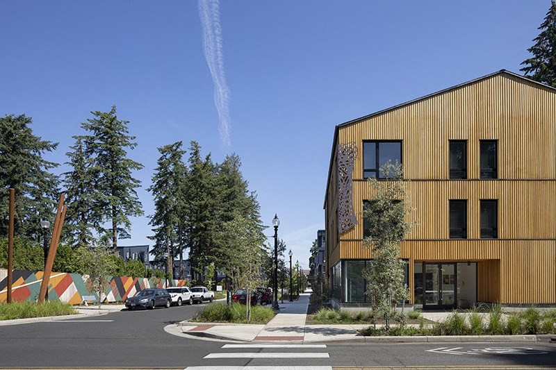 a city street with a yellow building on the left and trees on the right