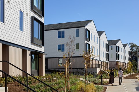 A row of modern houses with a person walking in front of them.